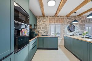 a kitchen with blue cabinets and a stone wall at Villa Green Garden in Hreljin