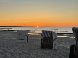 ツェンピンにあるFerienwohnung Stefanieのビーチでの夕日時の芝生の椅子2脚