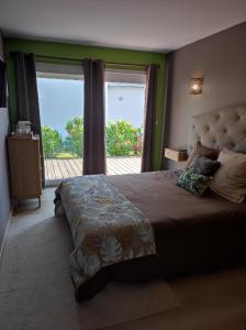 a bedroom with a large bed with a large window at Le Clos Fleuri proche de Bordeaux in Saint-Sulpice-et-Cameyrac