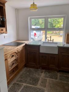 uma cozinha com um lavatório e uma grande janela em One Bedroom Rural Cottage with Hot tub em Whitegate