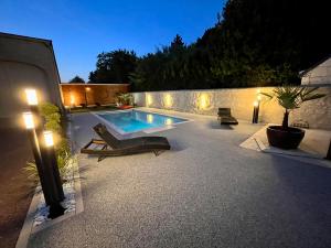 un patio trasero con piscina por la noche con luces en Cave Auger La Maison d'Hôtes en Restigné
