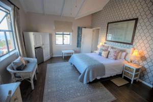 Mariner Guesthouse & Villa في سيمونز تاون: غرفة نوم بسرير كبير عليها لوحة كبيرة على الحائط