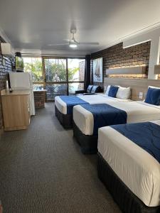 una camera d'albergo con tre letti e una televisione di Logan City Motor Inn a Slacks Creek