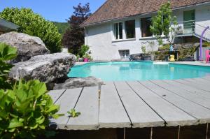 einen Pool mit einer Holzterrasse neben einem Haus in der Unterkunft Moulin de la Cuse - L'îlote in Cusance