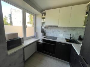 a kitchen with white cabinets and a sink and a window at Cozy apartment in Jūrmala