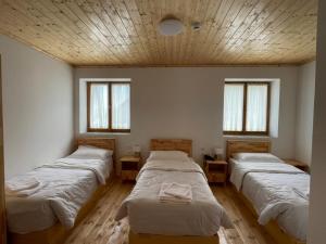 três camas num quarto com três janelas em Hotel Vermoshi TDC em Vermosh