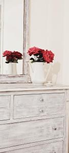 two white vases with red flowers on top of a dresser at Todea House in Reghin