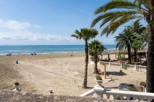 a view of a beach with palm trees and the ocean at HOSTEL PRIME in Benicàssim