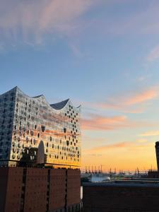 een gebouw wordt getoond met een zonsondergang op de achtergrond bij Schöne Wohnung mit Elbblick in Blankenese Strandlage in Hamburg