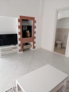 ein Wohnzimmer mit einem TV und einem weißen Boden in der Unterkunft Sant'Anna Guest House in Noicattaro