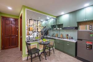 a kitchen with green cabinets and a table and chairs at SaziHome Ton That Tung Apartment in Ho Chi Minh City
