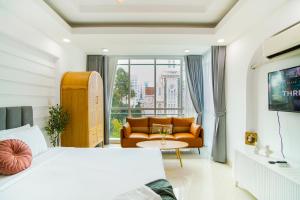 a bedroom with a bed and a couch and a window at SaziHome Ton That Tung Apartment in Ho Chi Minh City