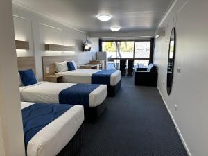 a hotel room with three beds and a desk at Logan City Motor Inn in Slacks Creek