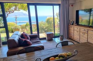 a living room with a table and a large window at Mariner Guesthouse & Villa in Simonʼs Town