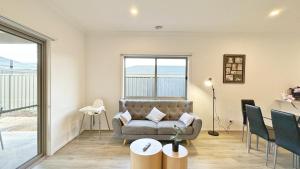a living room with a couch and a table at The Grove Townhouse by GoodLive in Tarneit