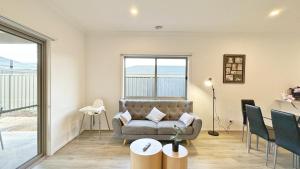 a living room with a couch and a table at The Grove Home by GoodLive in Tarneit