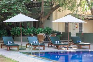 a group of chairs and umbrellas next to a pool at Hotel Ranthambore Regency in Sawāi Mādhopur