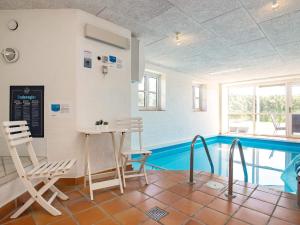 a room with a pool and a table and chairs at 8 person holiday home in Bl vand in Blåvand