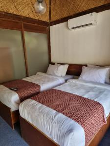 2 Betten in einem kleinen Zimmer mit in der Unterkunft puunee guest house & restaurant in Mendut