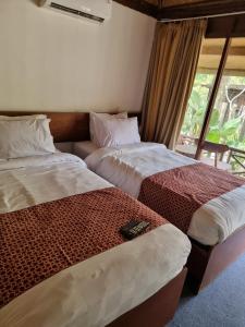 2 Betten in einem Zimmer mit Fenster in der Unterkunft puunee guest house & restaurant in Mendut