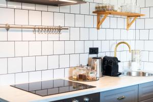 - un comptoir de cuisine avec évier et des murs carrelés blancs dans l'établissement Silvie Apartments - Masaryk, à Olomouc