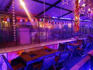 マナリにあるTrippy Shiva Hostelの紫色の照明、テーブルと椅子が備わるバー