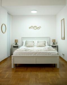 Una cama blanca en una habitación blanca con dos mesas. en Shabby Roman Studio- ai fori Imperiali, en Roma