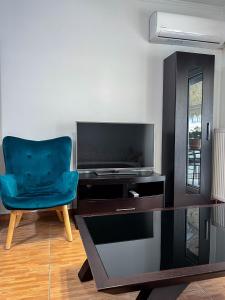 un salon avec une chaise bleue et une télévision dans l'établissement Philoxenia Oasis Supreme Apartment, à Alexandroúpolis