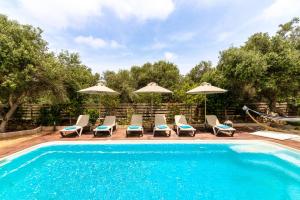 a swimming pool with chairs and umbrellas next to a pool at Villa Korina in Tria Monastiria