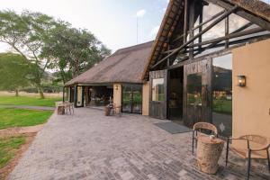 un patio exterior de un edificio con mesas y sillas en Okapuka Safari Lodge en Windhoek