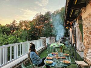 una mujer sentada en una mesa en un balcón en Le Manoir du Cerf en Gaillon