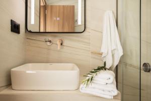 ein Badezimmer mit einem Waschbecken, einem Spiegel und Handtüchern in der Unterkunft Krystalias luxury studio in Psarou