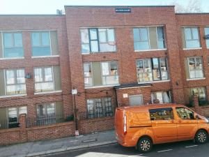 una furgoneta naranja estacionada frente a un edificio de ladrillo en Cosy Two Bedroom Apartment en Londres