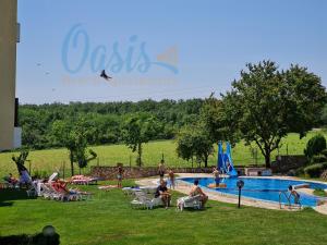 a group of people sitting around a swimming pool at Oasis Beach Apartments Kamchia in Kamchia