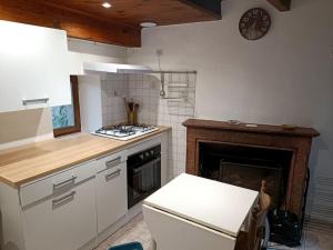 a kitchen with a stove top oven next to a fireplace at Maison de village in Sisco