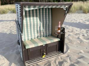 a chair in the sand with a bottle and a drink at Apartment Ostseerose in Zempin