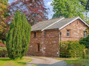 un vieux bâtiment en briques avec un arbre devant lui dans l'établissement Cairngarth Cottage, à How