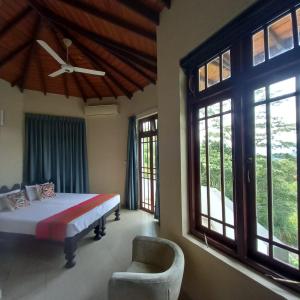 a bedroom with a bed and a chair and windows at Crown hills kandy in Kandy