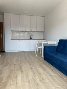 sala de estar con sofá azul y cocina en Apartament przy plaży - Rowy, en Rowy