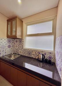 eine Küche mit einem Fenster über einem Waschbecken und einer Theke in der Unterkunft AJ BOUTIQUE HOTEL in Yogyakarta