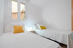 two beds in a room with two windows at Sara in L'Aldea