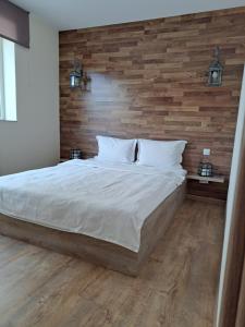 1 dormitorio con 1 cama grande y pared de madera en Todea House, en Reghin