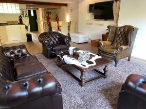 a living room with leather furniture and a coffee table at B&B de Muldermolen in Schinnen
