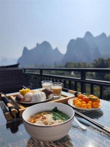 een tafel met een kom soep en borden eten bij Yangshuo Shanshuiyao Resort - Free Train Station Pick Up and Drop Off in Yangshuo