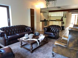 a living room with leather furniture and a coffee table at B&B de Muldermolen in Schinnen