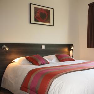 a bedroom with a large bed with a wooden headboard at Côté Hôtel in Légny