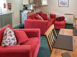 a living room with two red couches and a table at Pentargon View in Boscastle