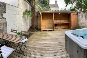 a wooden deck with a hot tub next to a building at La petite maison de Justin - Jacuzzi privatif in Bagnères-de-Bigorre