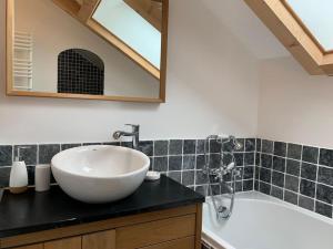 a bathroom with a white sink and a bath tub at La petite maison de Justin - Jacuzzi privatif in Bagnères-de-Bigorre
