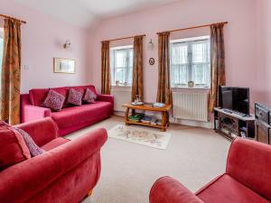 湯普科姆的住宿－南丁格爾鄉村別墅，客厅配有红色沙发和电视